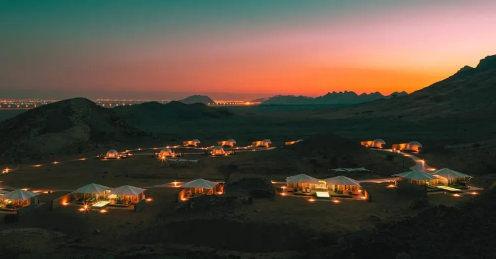 Illuminated lodges spread across a mountain valley at sunset