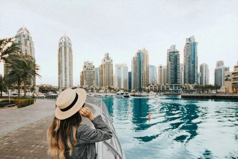 Viaggiatrice accanto a una piscina affacciata sulle torri di Dubai Marina