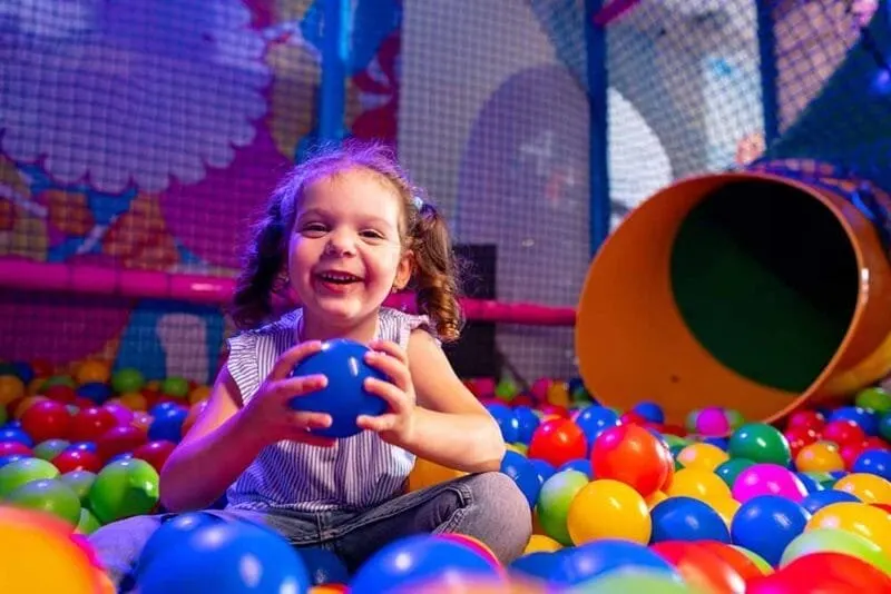Niña jugando en una piscina de bolas de colores