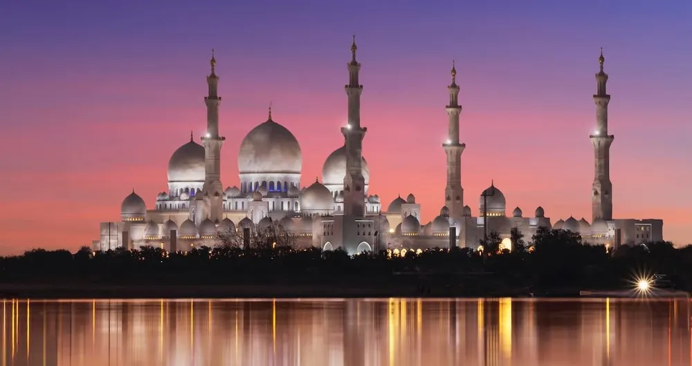 Mosque domes and minarets reflected in water at dusk