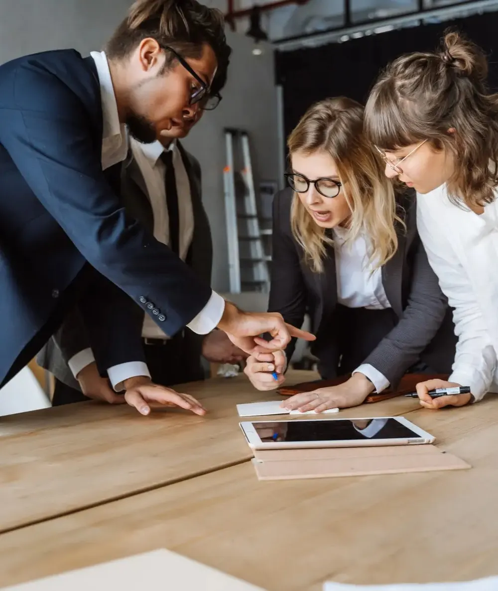 Three people reviewing documents around a meeting table