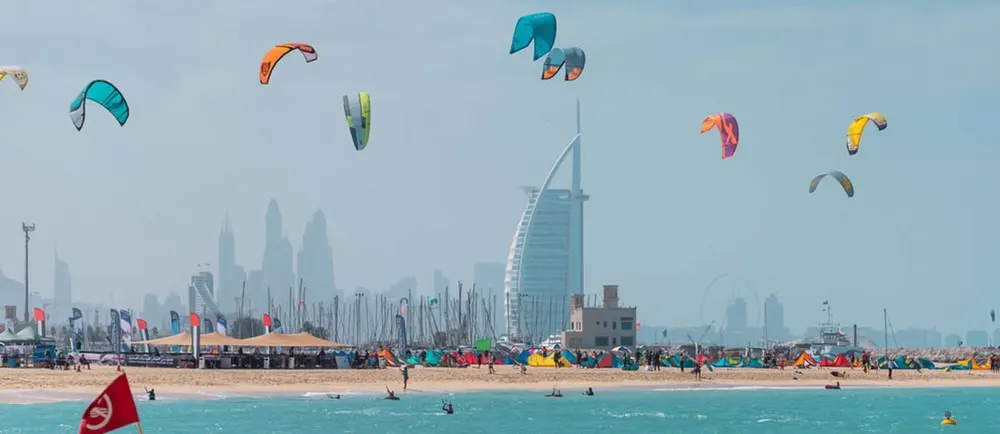 Voiles de kitesurf au-dessus d’une plage avec le Burj Al Arab au loin