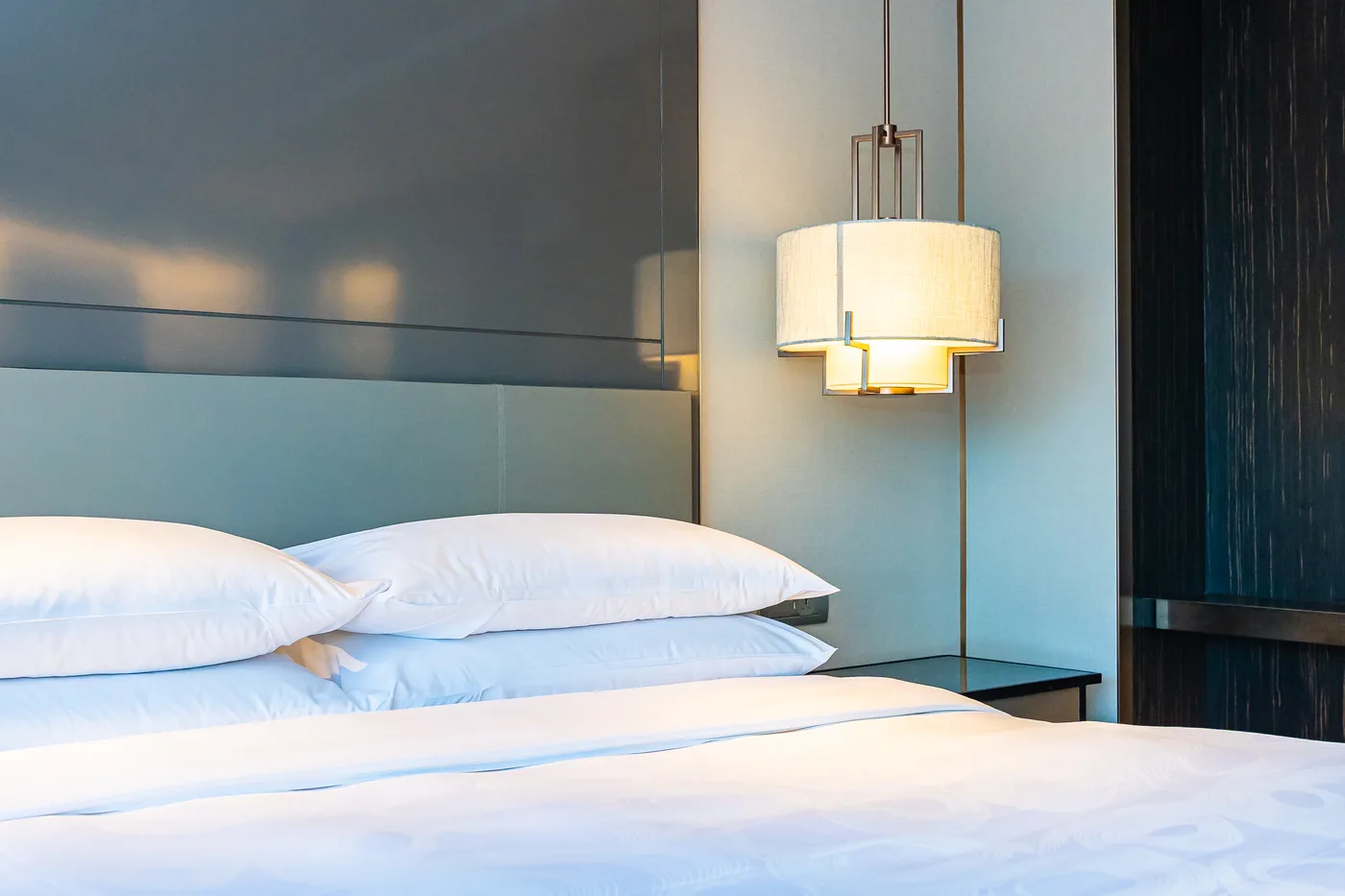 White pillows and a hanging bedside lamp