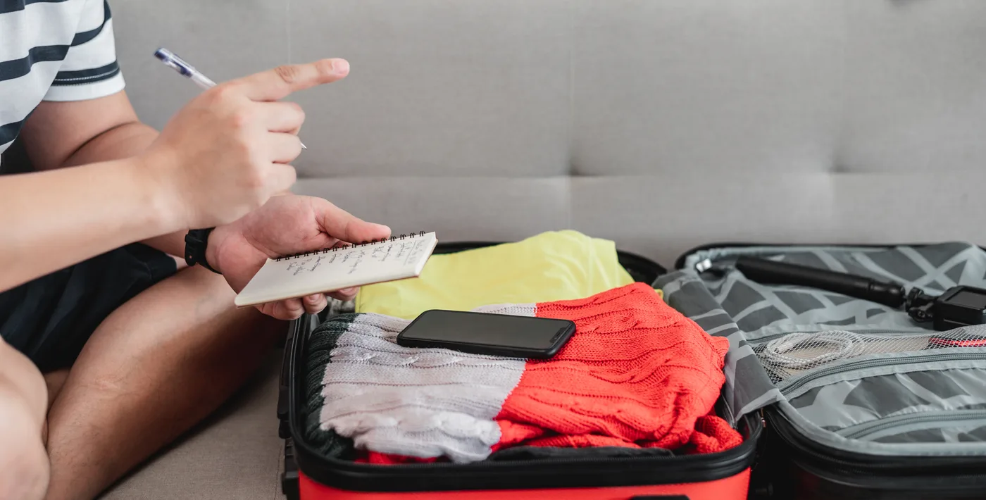 Viaggiatore che controlla una lista accanto alla valigia
