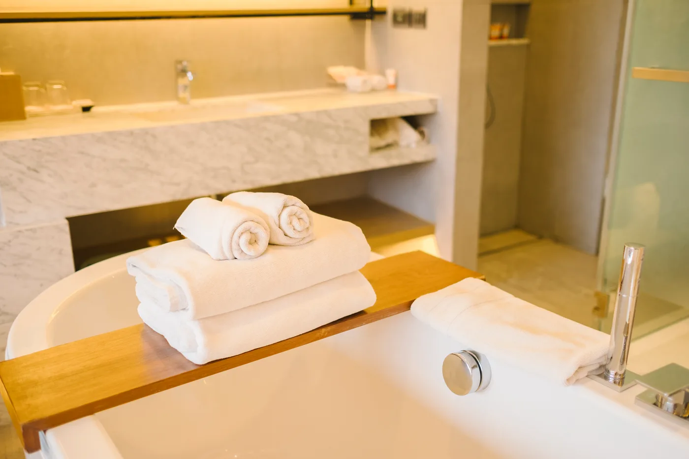 Bathtub with a wooden tray and rolled white towels