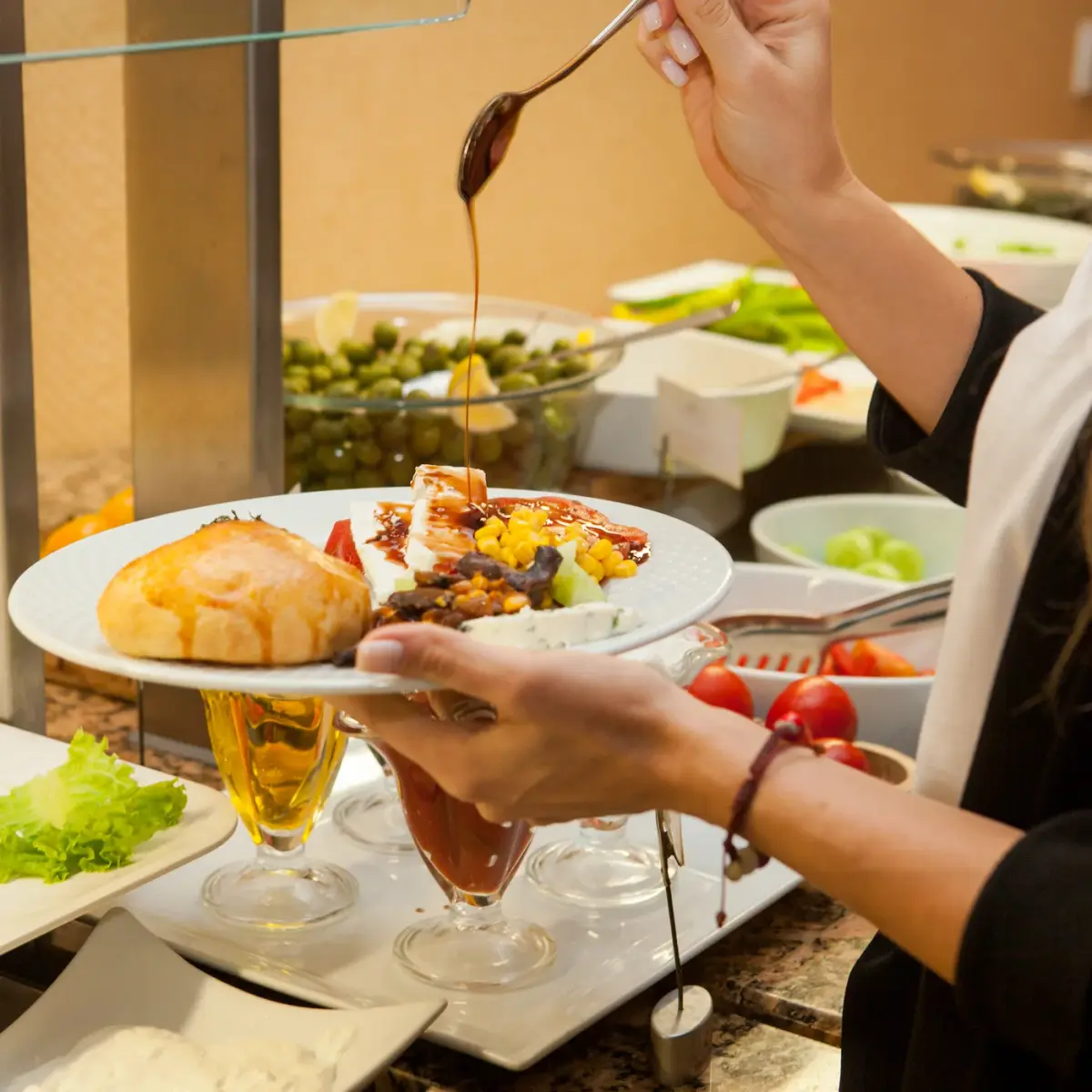 Person selecting food from a buffet with a serving spoon