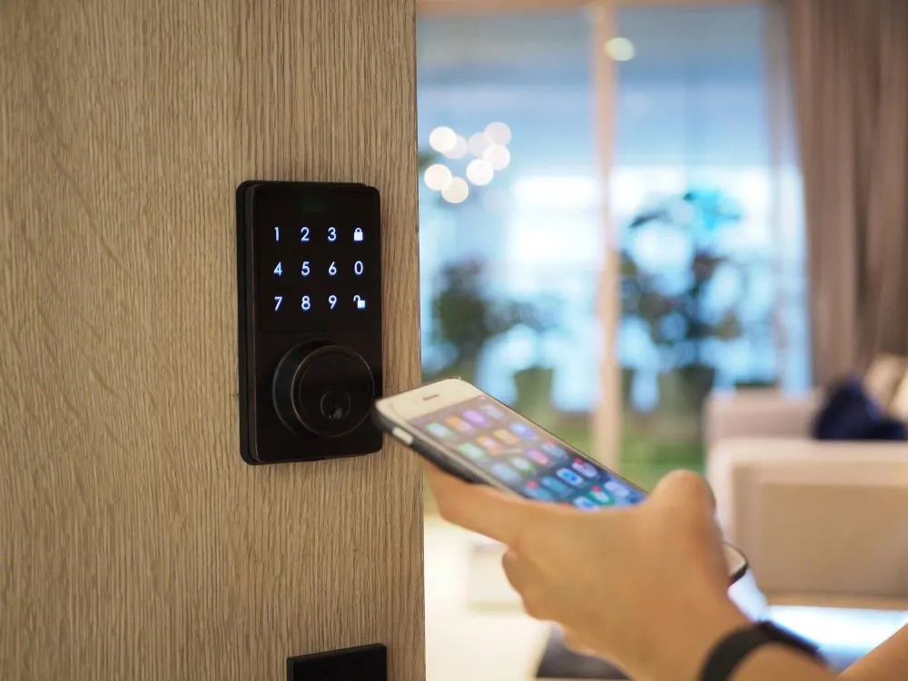 Mano che regge uno smartphone accanto a una serratura elettronica