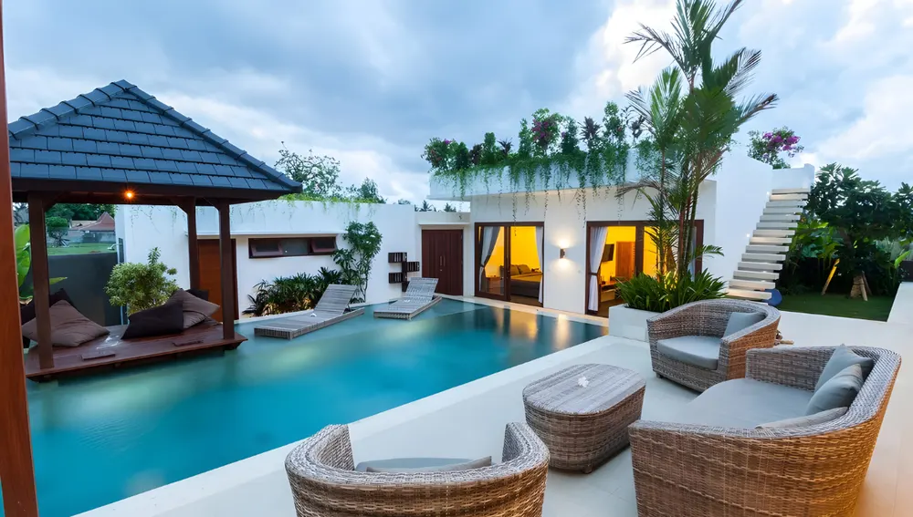 Cortile di una villa con piscina e sedie da esterno intrecciate