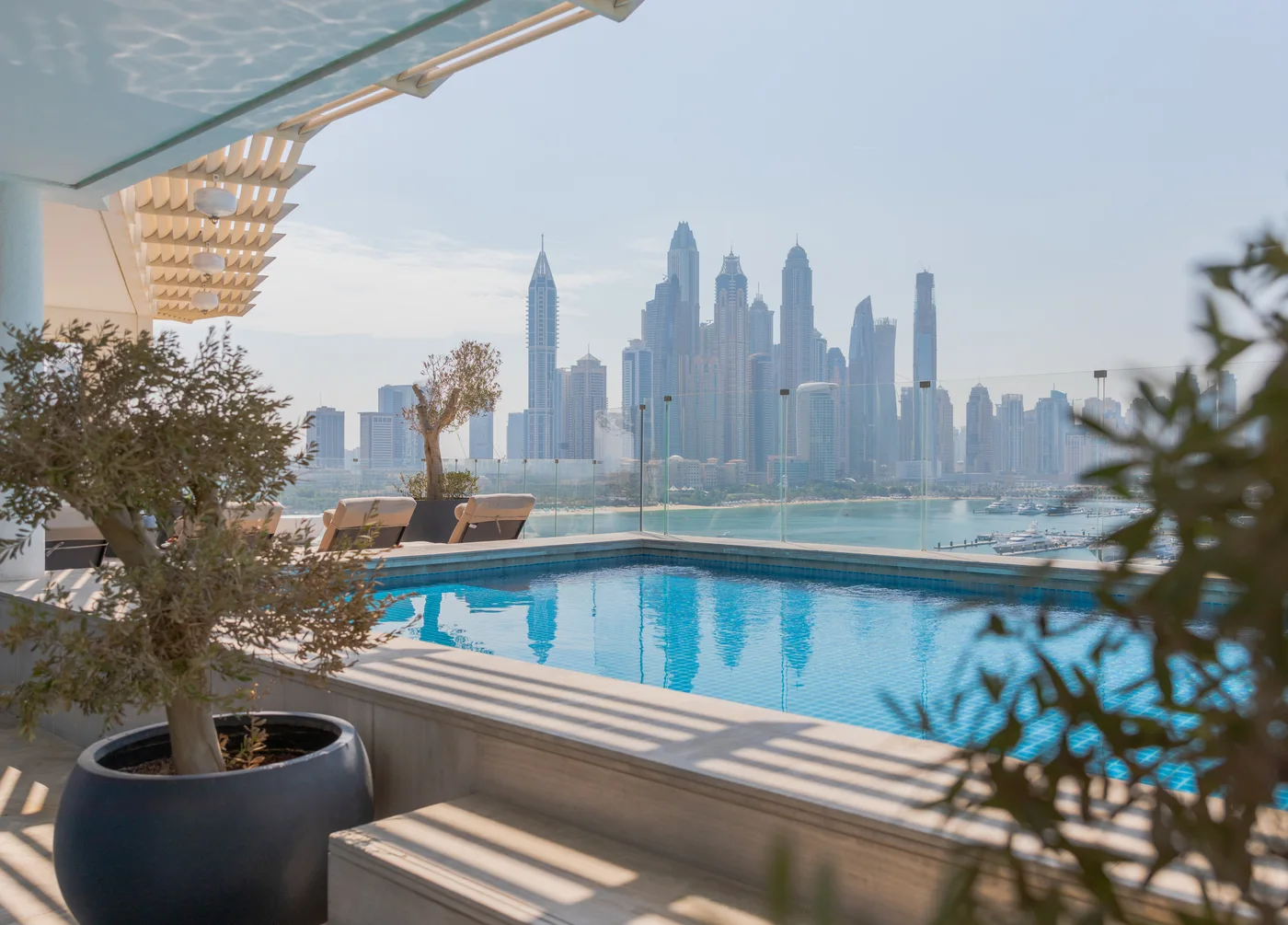 Private terrace swimming pool at the three-bedroom FIVE Palm penthouse with Dubai skyline beyond